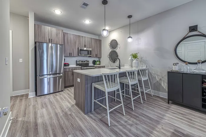 Raymore, MO Apartments for Rent - Encore - Kitchen with an Island, Hanging Light Fixtures, and Stainless-Steel Appliances