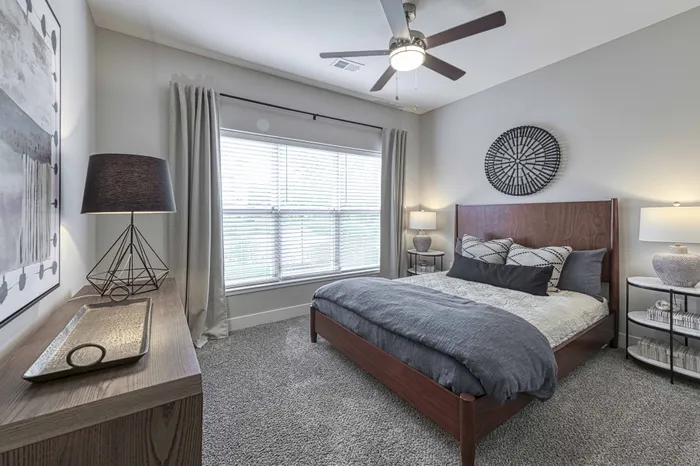 Raymore, MO Studios for Rent - Encore - Bedroom with a Ceiling Fan, Carpeting, and a Large Window
