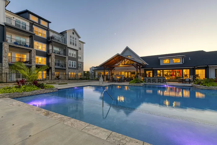 Pet-Friendly Apartments in Raymore, MO - Encore - Pool with a View of Apartment Complex and Lounge Chairs