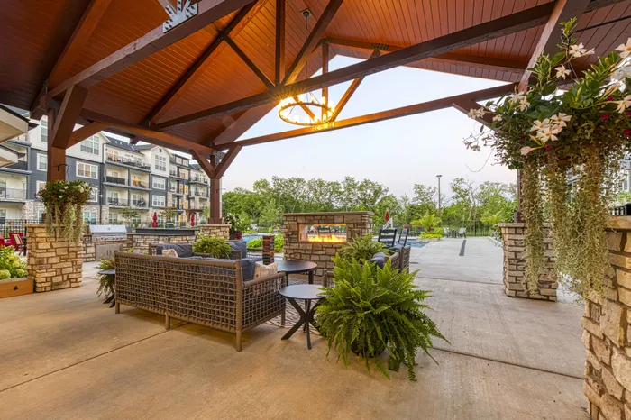 Dog-Friendly Apartments in Raymore, MO - Encore - Outdoor Fireplace with Patio Furniture inside a Semi-Enclosed Space