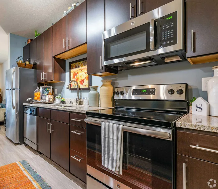 Contemporary kitchen with stainless steel appliances and dark wood cabinets.