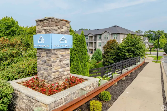 Inviting entrance of Springhouse apartments with lush greenery and modern stone signage.