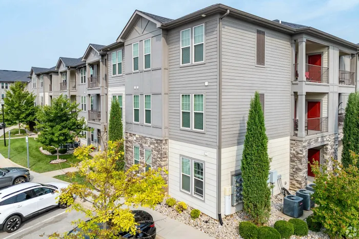 Modern apartment building with stylish siding, lush landscaping, and ample parking.