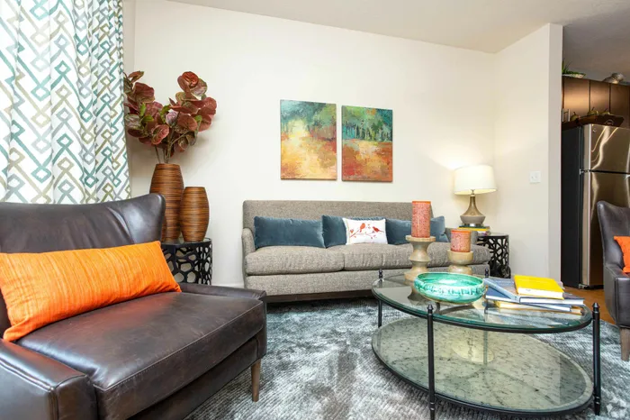 Contemporary living room with leather chairs, a textured sofa, vibrant cushions, and modern decor accents.