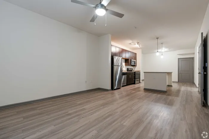 Bright open-concept kitchen with stainless steel appliances and a contemporary living area with hardwood floors.