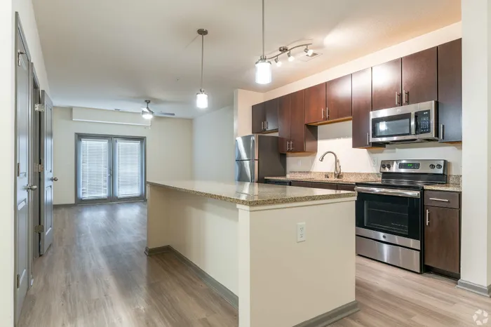 Bright, modern kitchen with sleek dark cabinets, stainless steel appliances, and spacious countertops leading to an open living area with elegant French doors.