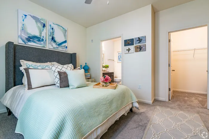 Bright and cozy bedroom with art above the bed, featuring soft lighting and a welcoming atmosphere.