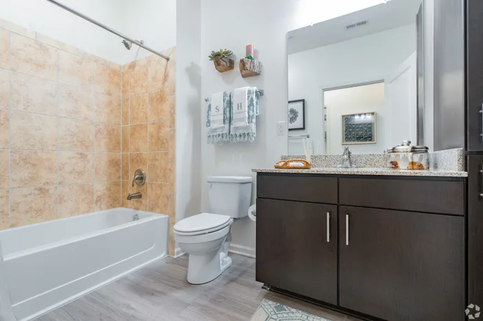 Elegant bathroom featuring glossy tiles, a modern vanity with granite countertop, and stylish decor.