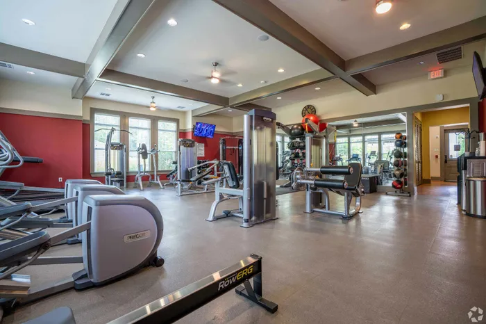 Modern fitness center with a variety of exercise equipment, large windows, and a stylish interior design.