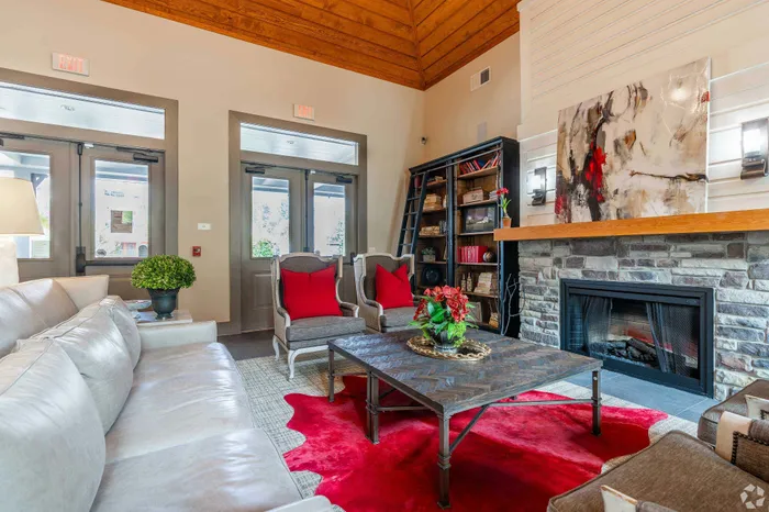 Charming living room with a stone fireplace, stylish gray furniture, vibrant red accents, and a modern art piece.