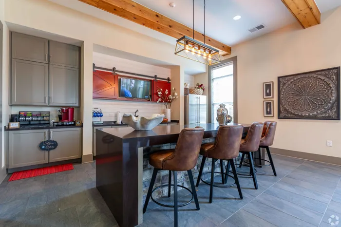 Chic kitchen area with sleek bar counter, leather stools, and stylish pendant lighting.