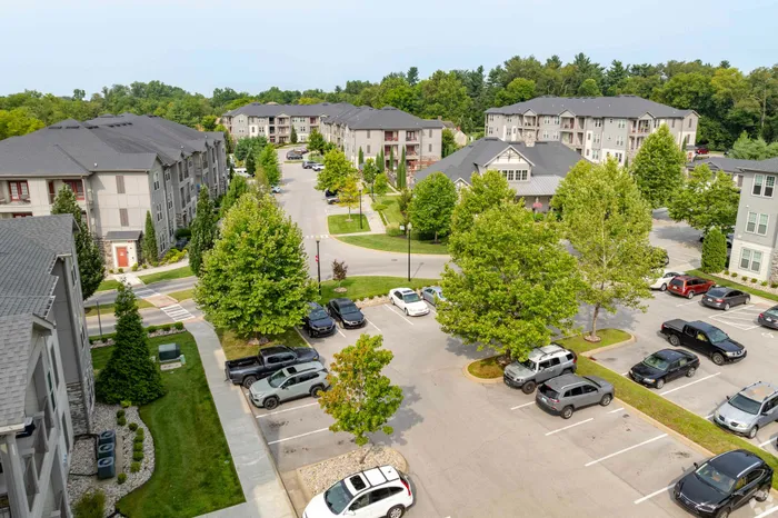 Aerial view of a picturesque apartment community with lush greenery and spacious parking.