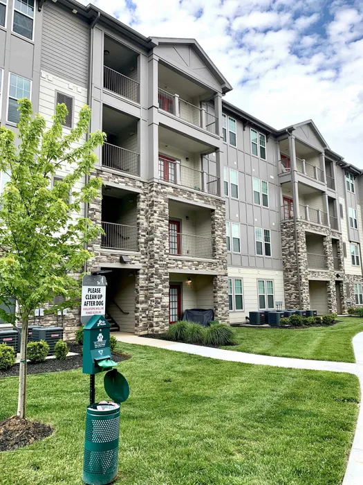 Modern apartment complex with stone accents and spacious balconies, surrounded by well-maintained lawns and greenery.