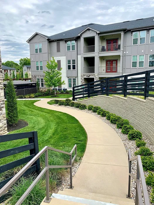 Modern apartment building with stylish balconies and beautiful landscaped pathways, surrounded by lush greenery.