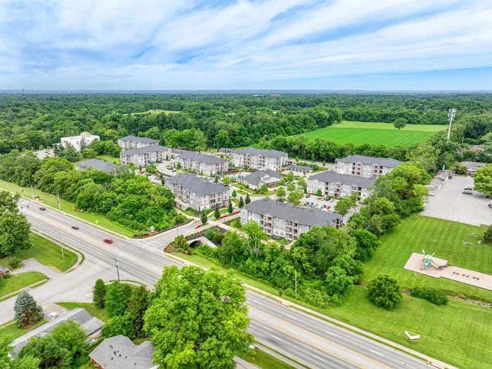 Stunning aerial view of modern apartment complex surrounded by lush greenery, offering serene living in a peaceful location.