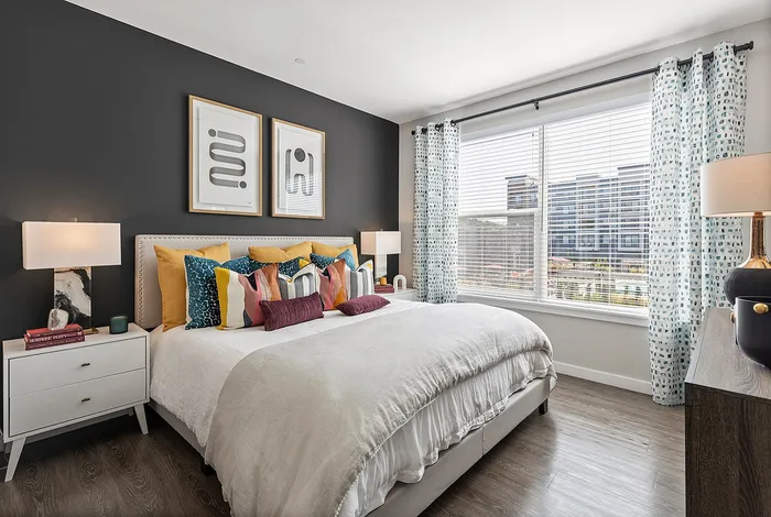 Elegant bedroom with modern decor, featuring a king-size bed adorned with colorful pillows, stylish wall art, and a bright window view.