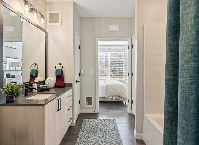 Contemporary bathroom with sleek vanity, modern lighting, and a view into a cozy bedroom featuring bright natural light.