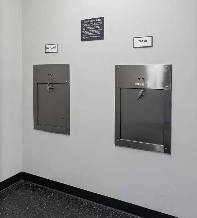 Efficient waste management room with designated recycling and trash chutes, promoting sustainability in modern living spaces.