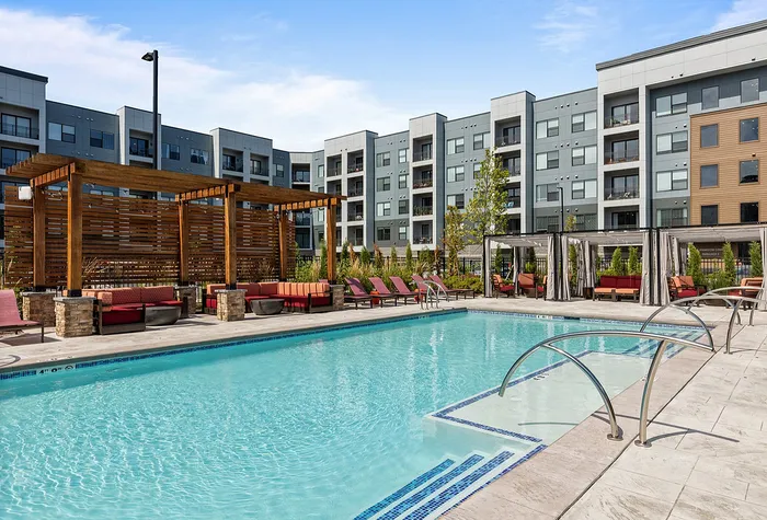 Luxurious apartment complex featuring a sparkling outdoor pool, stylish pergola seating areas, and modern architecture.