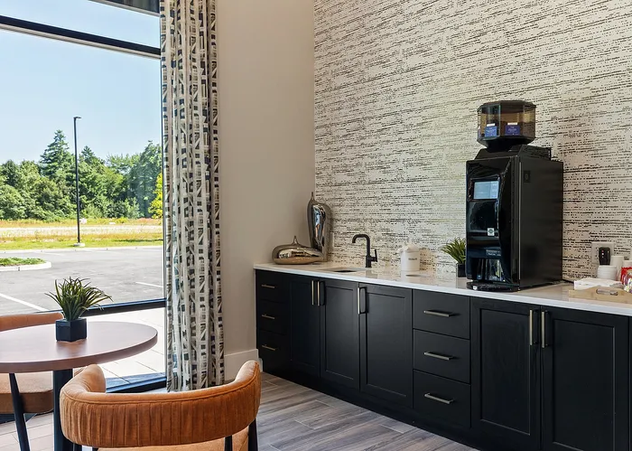 Chic apartment kitchenette with sleek black cabinets, modern backsplash, and large window offering scenic views.