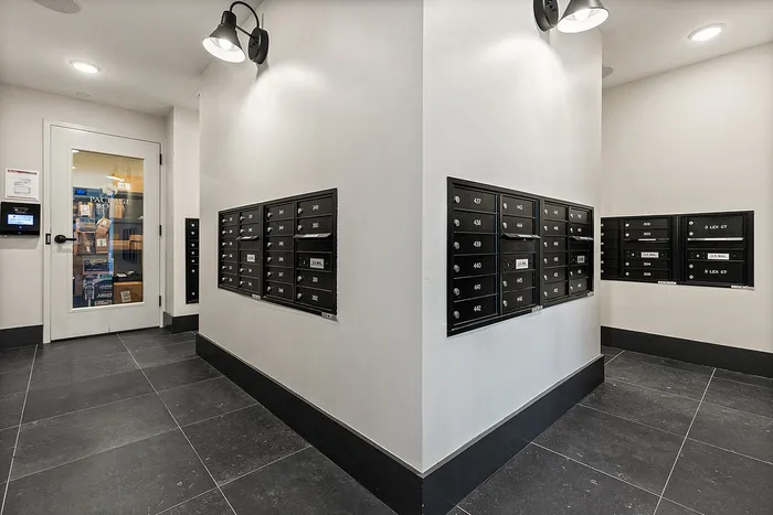 Modern apartment mailroom featuring sleek black mailboxes and a package room for convenient deliveries.