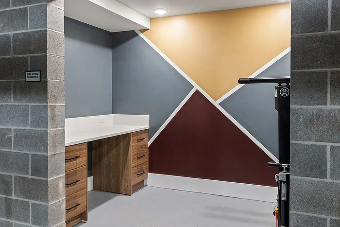 Modern bike repair workshop with vibrant geometric wall design and sleek wooden cabinets.