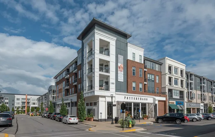 Charming modern apartment complex with upscale retail stores beneath, highlighting urban living with a vibrant storefront atmosphere.