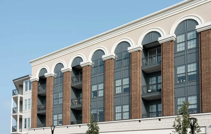 Elegant apartment building exterior featuring arched windows, brick facade, and private balconies, ideal for modern urban living.
