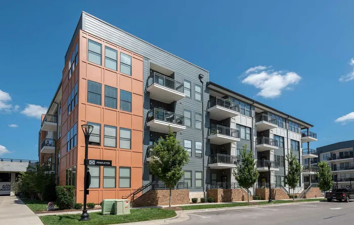 Modern apartment complex with vibrant facade and private balconies under a clear blue sky.