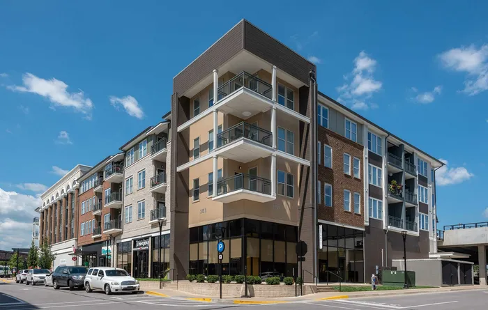 Modern apartment building with stylish balconies, large windows, and vibrant street view, perfectly capturing urban living.