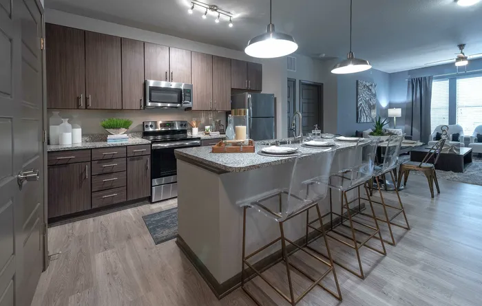 Modern open-concept kitchen and living room with sleek wood cabinetry, stainless steel appliances, and stylish seating, exuding elegance and comfort.
