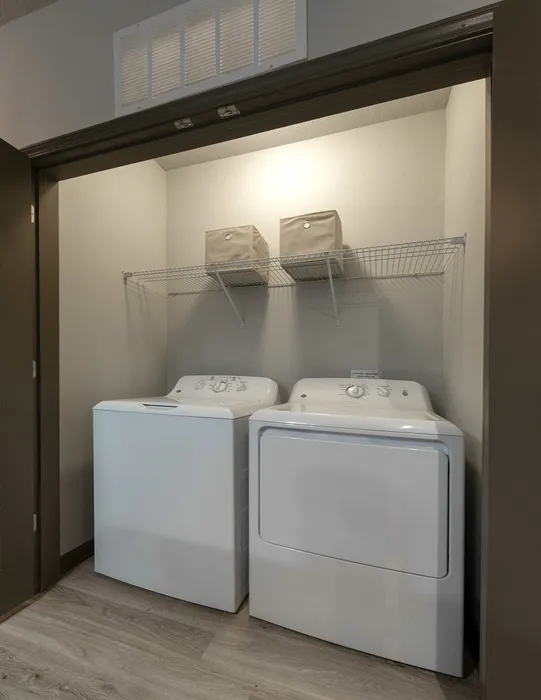 Chic laundry nook with modern washer and dryer, featuring sleek shelving for storage.