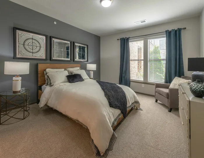 Inviting bedroom with elegant decor, featuring a plush bed, stylish artwork, and large window draped with chic curtains.