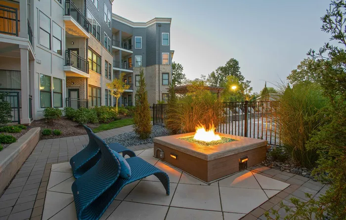 Chic apartment courtyard with modern fire pit, stylish seating, and lush landscaping, perfect for relaxing evenings.