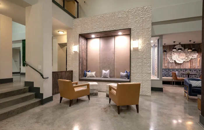 Elegant lobby space featuring modern seating, cozy built-in bench with accent pillows, and artistic wall decor under soft lighting ambiance.