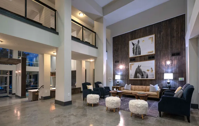 Chic and modern apartment lobby with high ceilings, cozy seating area, stylish wooden accent wall, and elegant decor.