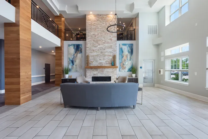 Luxurious open-concept living room with high ceilings, elegant stone fireplace, modern decor, and abundant natural light.