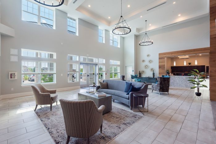 Elegant and spacious lobby with high ceilings, large windows, stylish seating, and contemporary chandeliers creating a welcoming atmosphere.