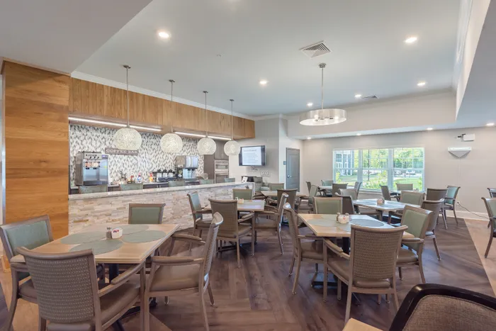 Elegant communal coffee bar with modern decor, featuring stylish pendant lights, ample seating, and large sunlit windows.