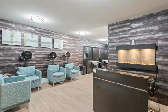 Modern salon suite featuring chic armchairs, wall art, and professional hair dryers, exuding a stylish and inviting ambiance.