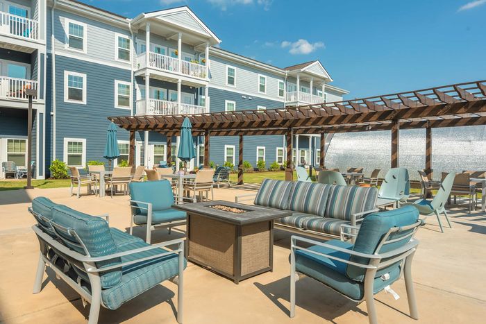 Charming outdoor patio area with stylish seating, pergola, and inviting courtyard ambiance at a modern apartment complex.