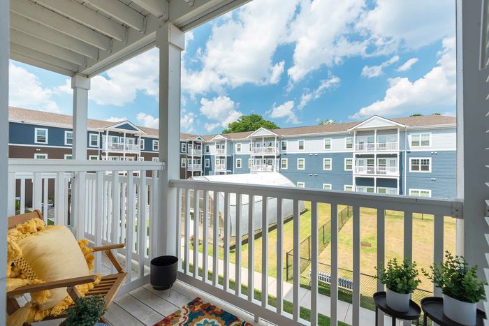 Charming balcony view of a modern apartment complex with vibrant blue skies and lush greenery, perfect for relaxation.