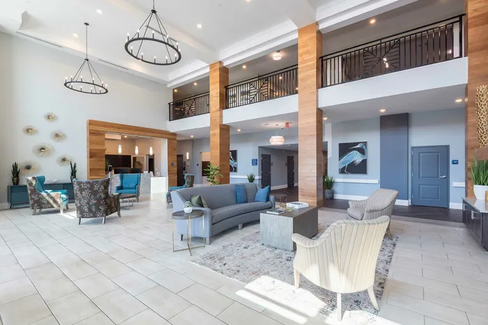 Elegant and spacious apartment lobby featuring modern decor, stylish seating, and grand chandeliers.