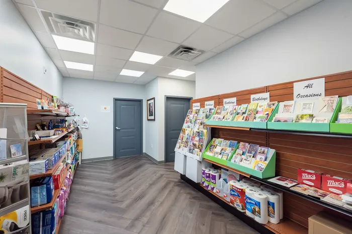 Bright and inviting store interior showcasing a variety of greeting cards for all occasions and everyday essentials on sleek wooden shelving.