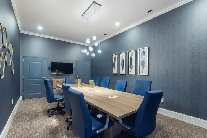 Elegant conference room featuring a modern wooden table, stylish blue chairs, contemporary lighting, and sleek wall art.
