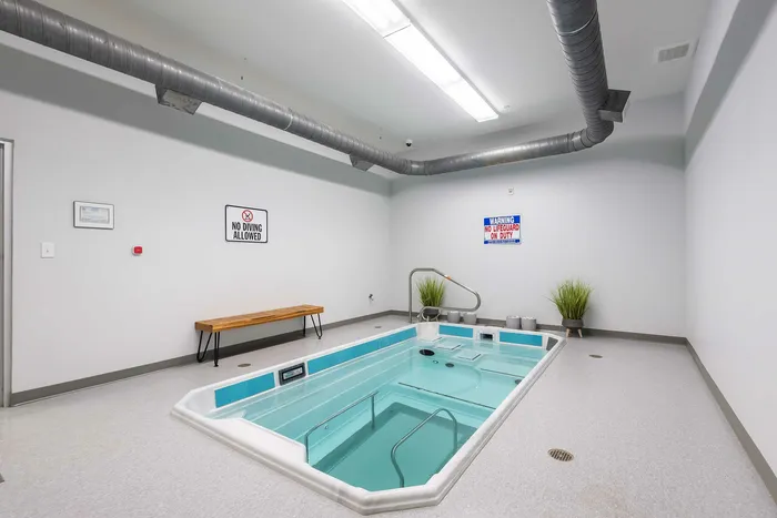 Sleek indoor lap pool area with modern ventilation, safety signage, and ambient lighting, perfect for relaxation and year-round swimming.