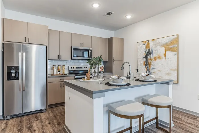 Modern kitchen with sleek stainless steel appliances, elegant wooden cabinets, and a stylish breakfast bar with cushioned stools, perfect for cozy dining.
