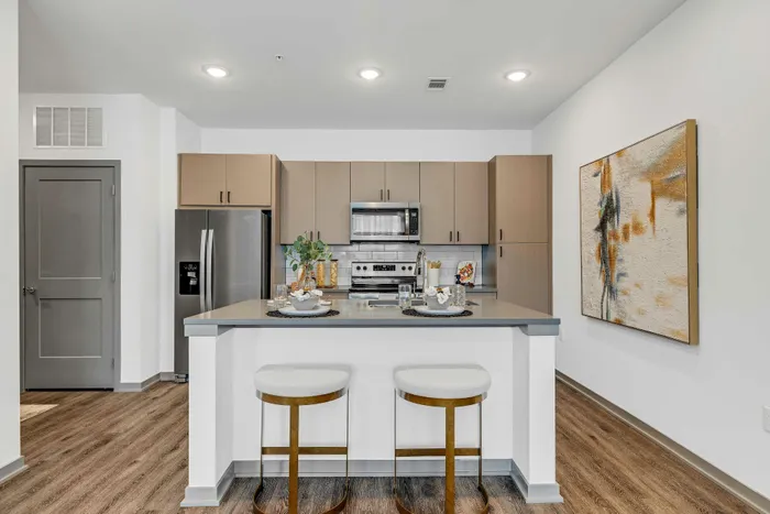 Modern kitchen with sleek stainless steel appliances, elegant island seating, and contemporary artwork enhancing the stylish space.