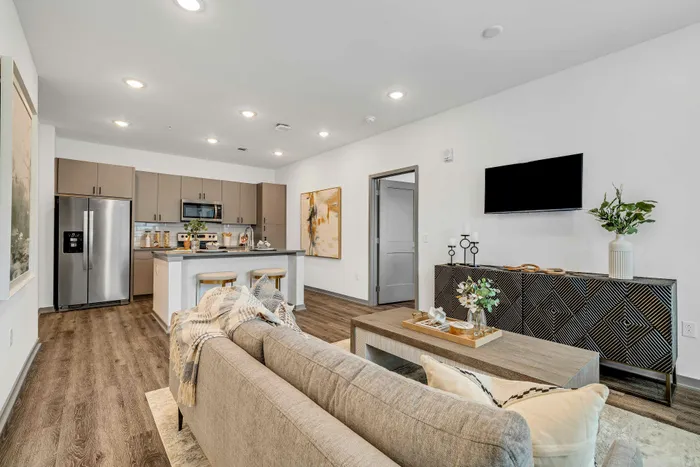 Modern open-plan living room with elegant kitchen, featuring stylish cabinetry and sleek appliances, complemented by a cozy seating area and tasteful decor.