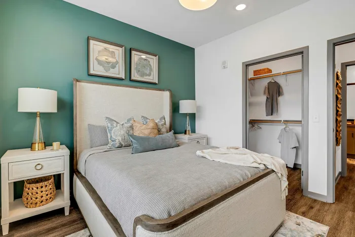 Inviting bedroom with elegant decor, featuring a plush bed, stylish bedside lamps, and an open closet, creating a cozy and modern atmosphere.